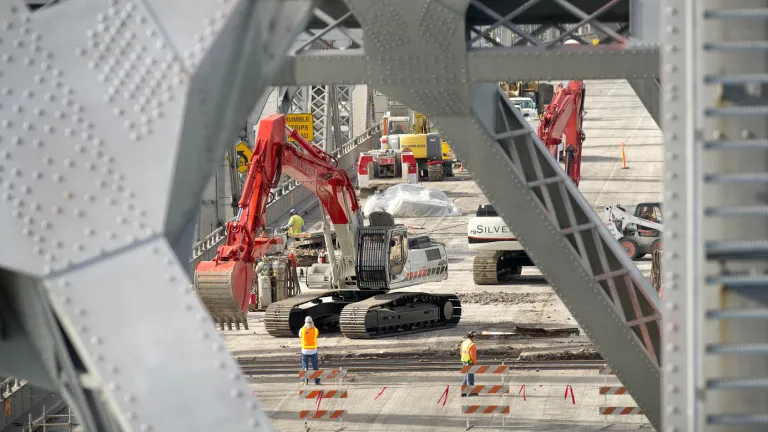 Using excavators, crews lift up chunks of deck and deposit them into trucks, being careful to contain the debris so as to avoid polluting the Bay below. 
