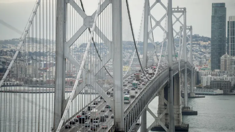 Cars travel west toward San Francisco on the upper deck of the Bay Bridge while SF's cityscape is in the background