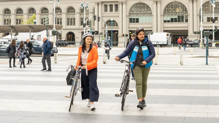 Two people walking their bicycles across a pedestrian plaza.