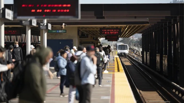 Passengers wait for an arriving BART train.