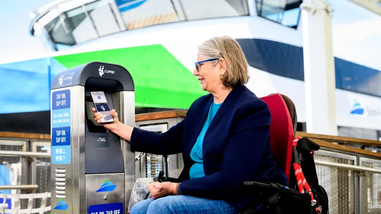 A person in a wheelchair pays for her ferry ride using a Clipper card.