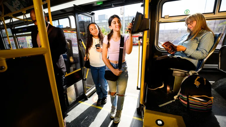 Teens tagging Clipper to pay as they board a Muni bus.