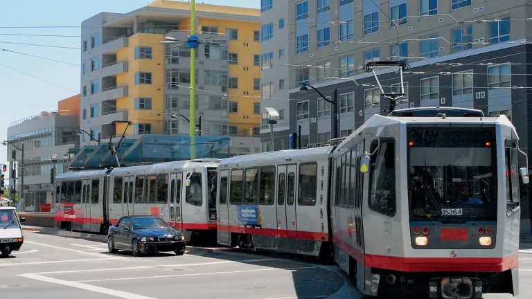 a Muni Metro streetcar glides past compact housing in San Francisco
