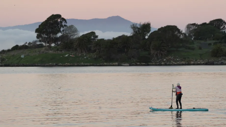 A stand-up paddleboarder on the water near the Bay Trail.