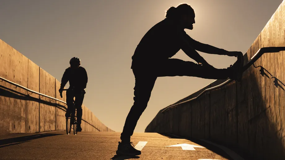 Silhouettes of a jogger stretching and a cyclist.