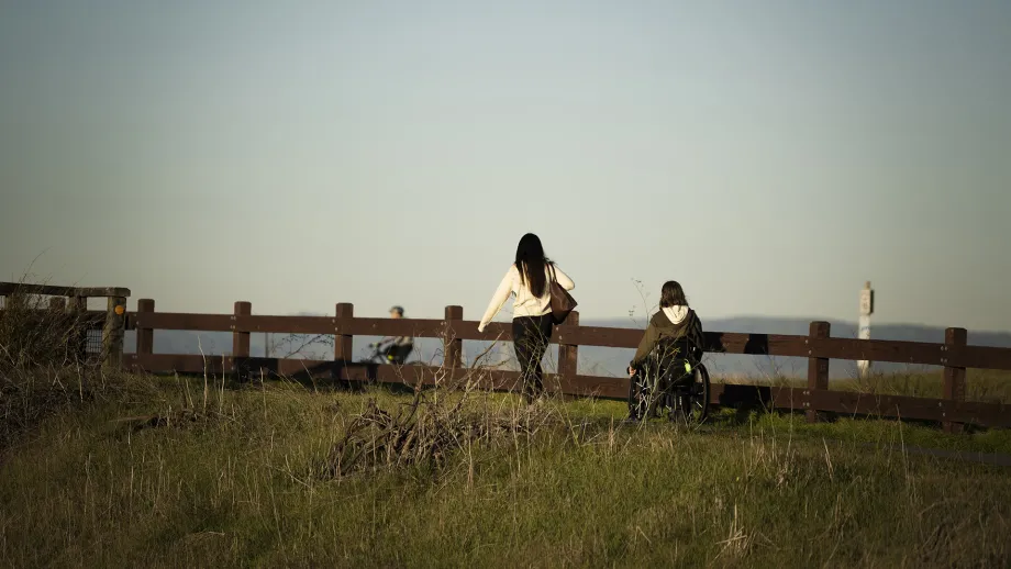 A walker and wheelchair user on a boardwalk on the Bay Trail.