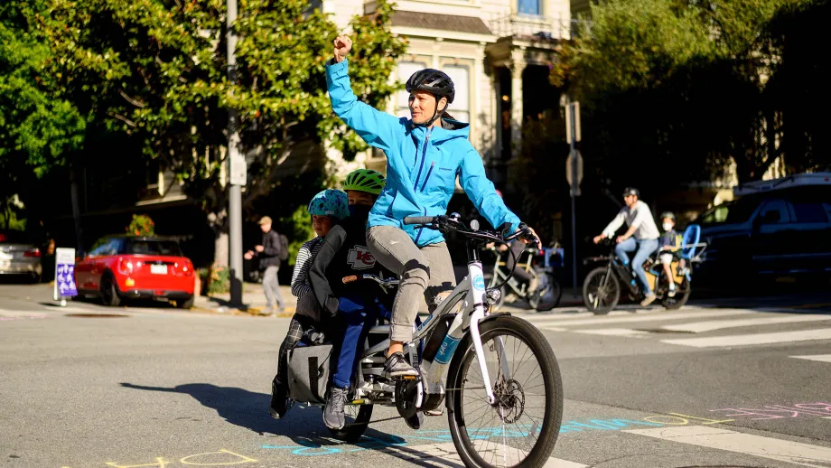 A family rides by on an electric bicycle on Bike to Wherever Day.