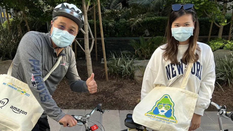 Two people with Bike to Wherever Day totebags.