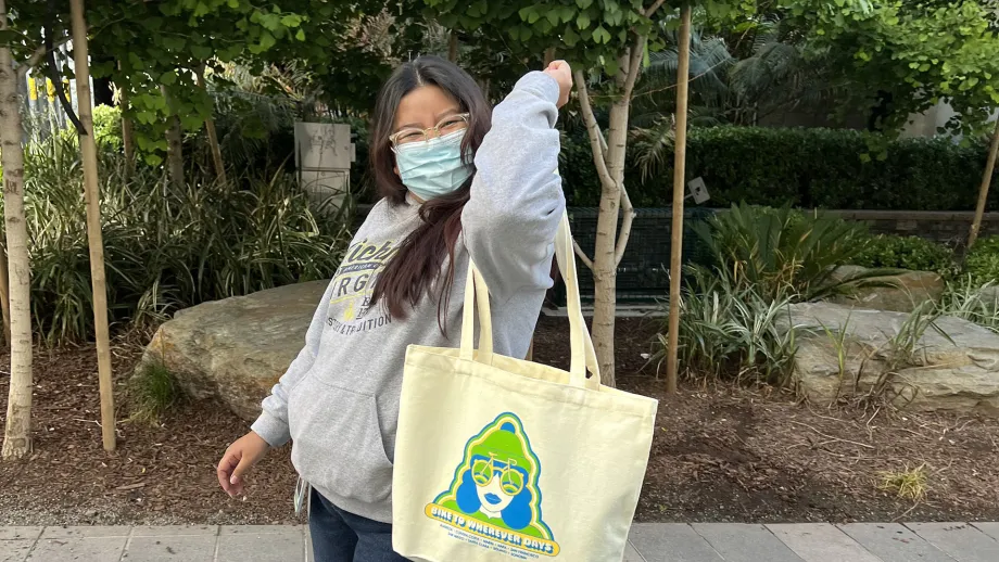 A woman shows off her new Bike to Wherever Day totebag.