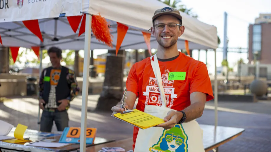 A Bike to Work Day volunteer holds out a clipboard.