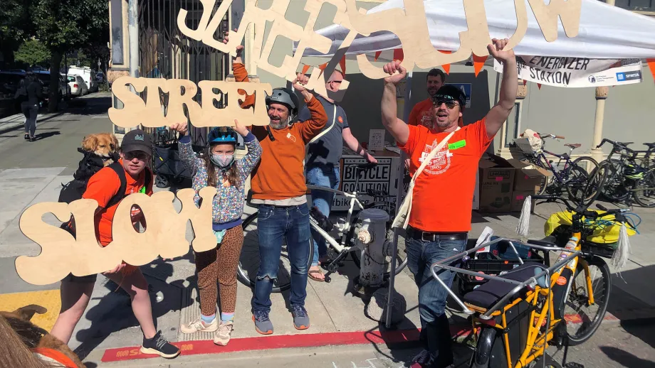 Bike to Work Day volunteers holding large Slow Street signs.