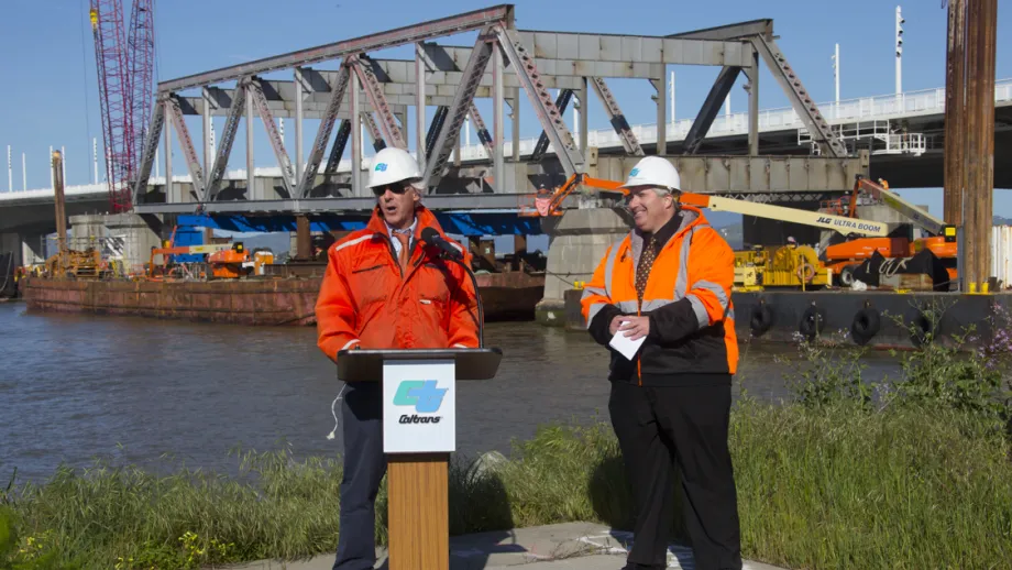 Man at podium talking to a crowd with truss behind him