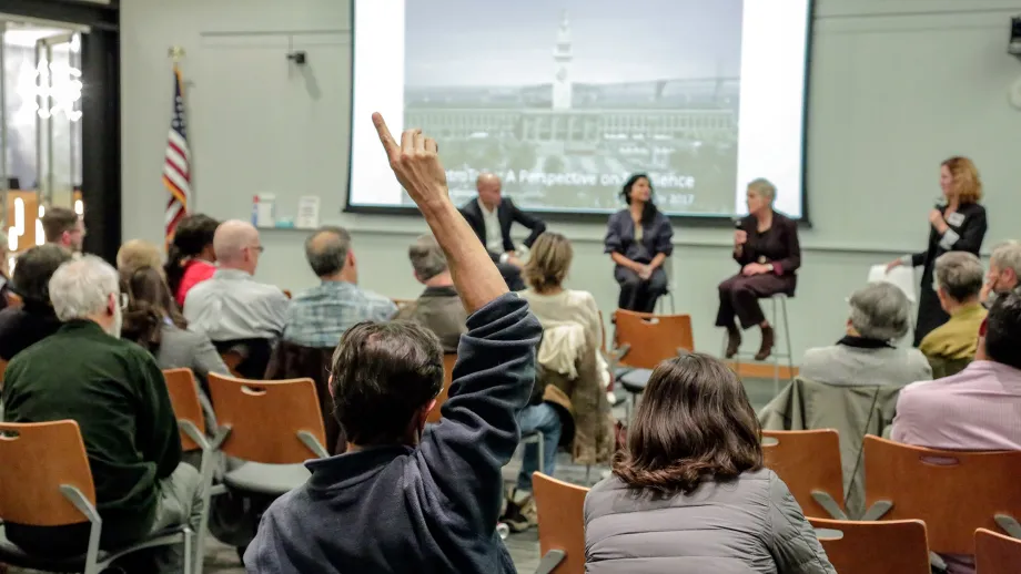 man in audience raises his hand