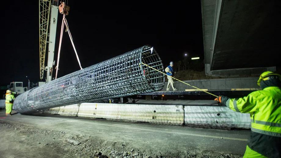 A crane picks up a pre-fabricated rebar cage to place in the pre-drilled shaft to reinforce the concrete for the express lane sign foundations.