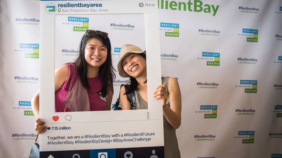 two women posing for a picture in front of Resilient Bay backdrop