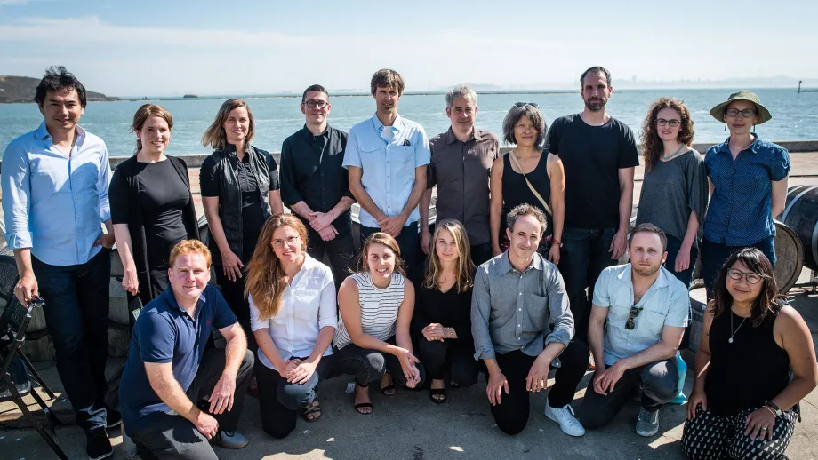 group of people posing for picture in front of water