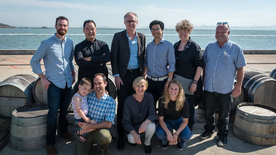 group of people posing for picture in front of water