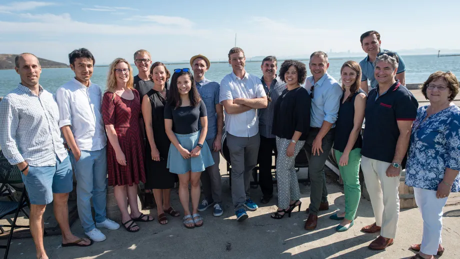 group of people posing for picture in front of water