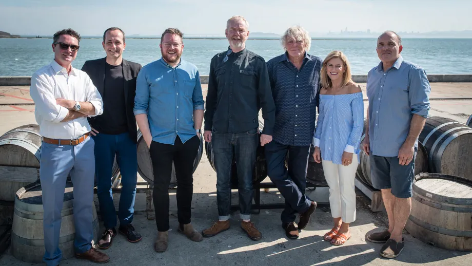 group of people posing for picture in front of water