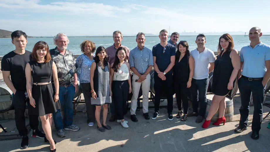 group of people posing for picture in front of water