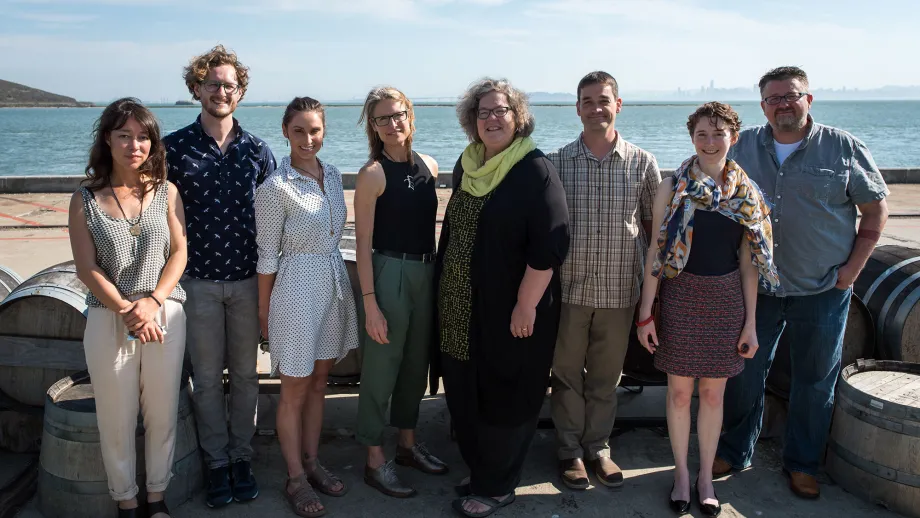 group of people posing for picture in front of water