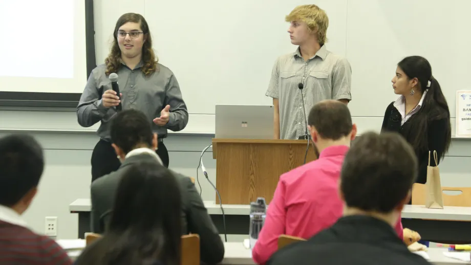 young adult holding microphone next to a podium