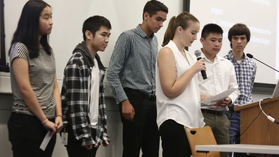 young adult holding microphone next to a podium