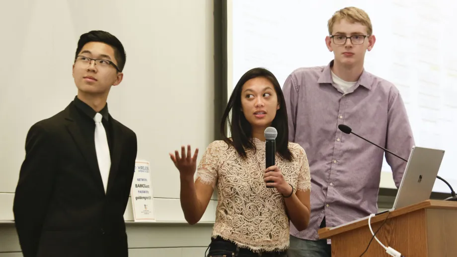 young adult holding microphone next to a podium