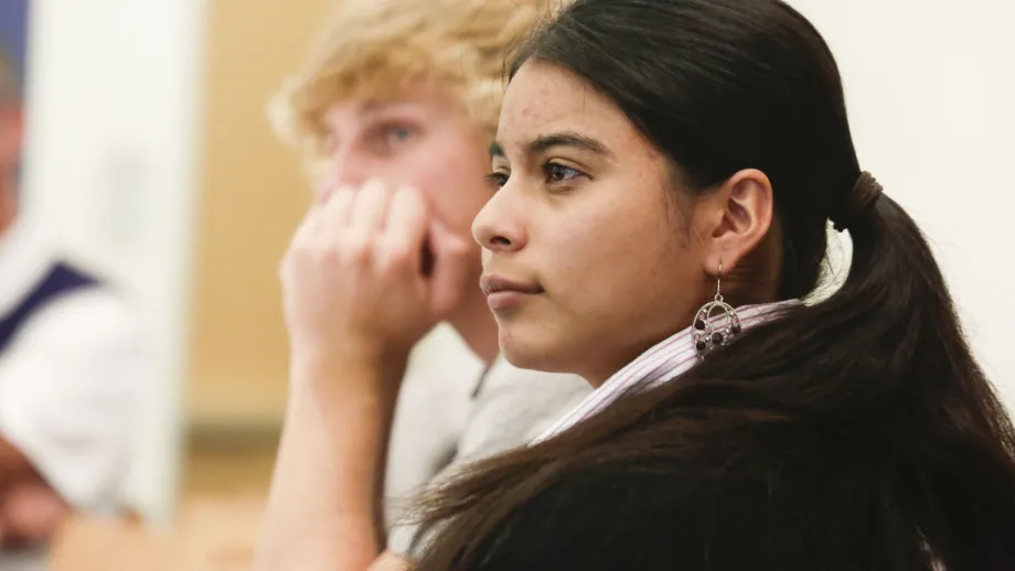 young adults sitting at tables listening to speakers