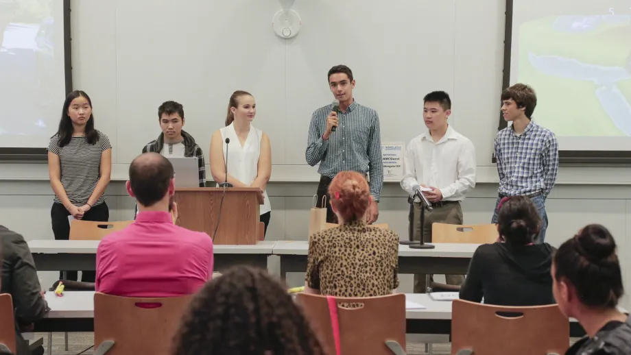 young adult holding microphone next to a podium