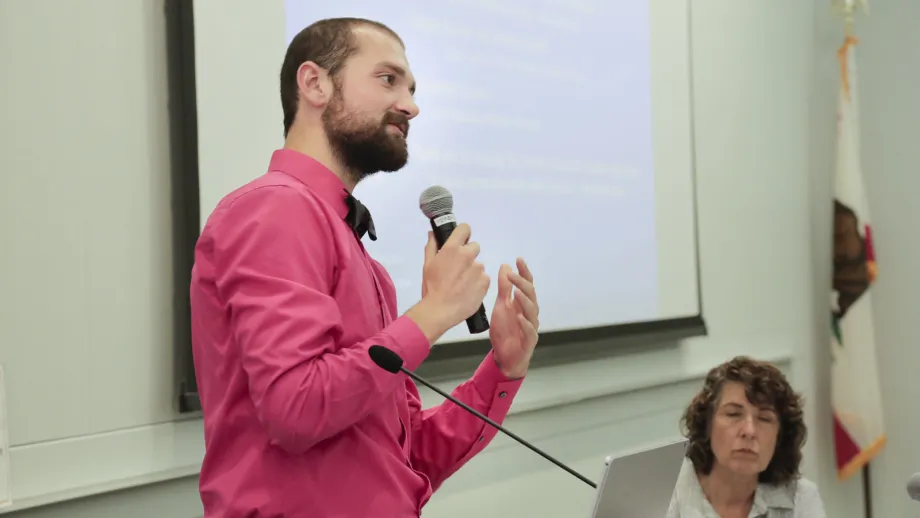 young adult holding microphone next to a podium