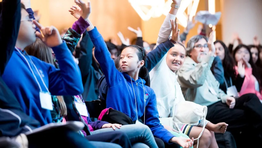 kids sitting in chairs raising their hands