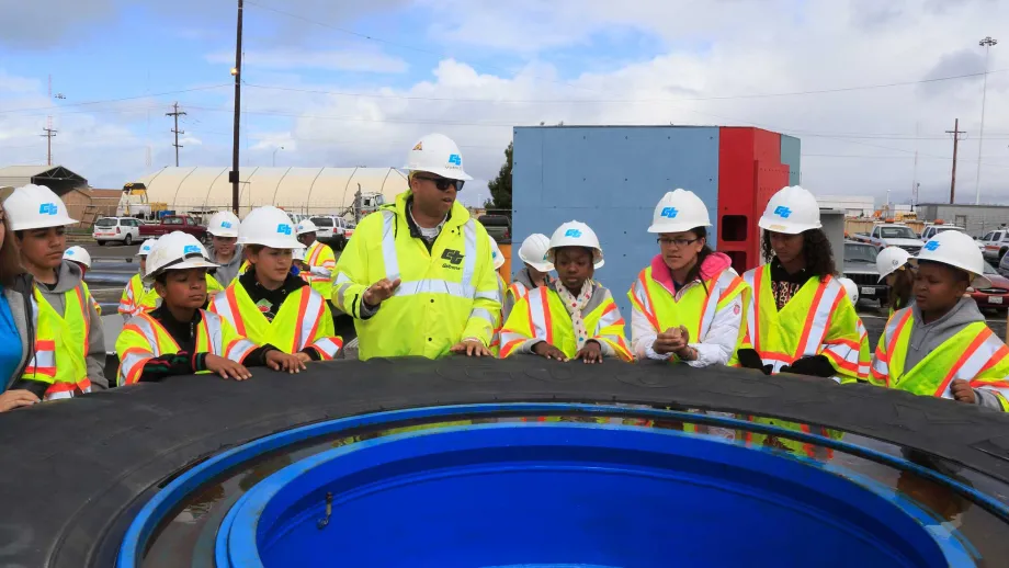 The energetic engineers-in-training gather around a model saddle carrier tire.
