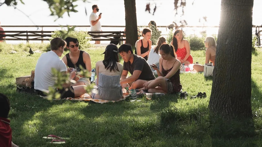 Young adults picnicking in the grass by the waterside.