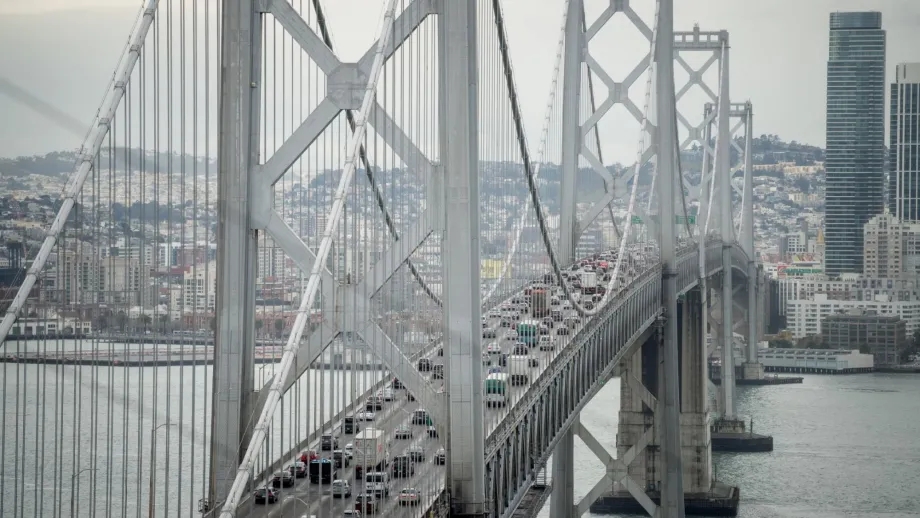 Cars travel west toward San Francisco on the upper deck of the Bay Bridge while SF's cityscape is in the background
