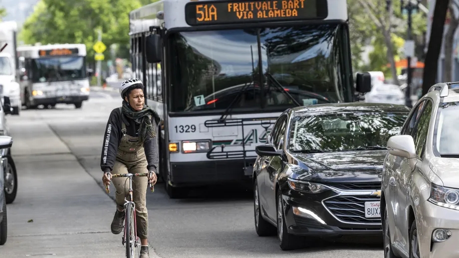 A cyclist rides next to traffic on the streets of Oakland.