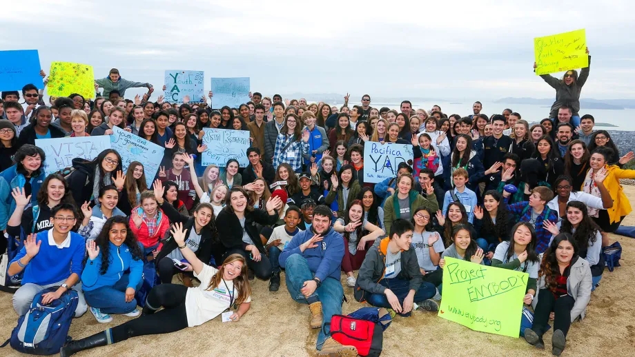 group of students posing for a picture in front of the water