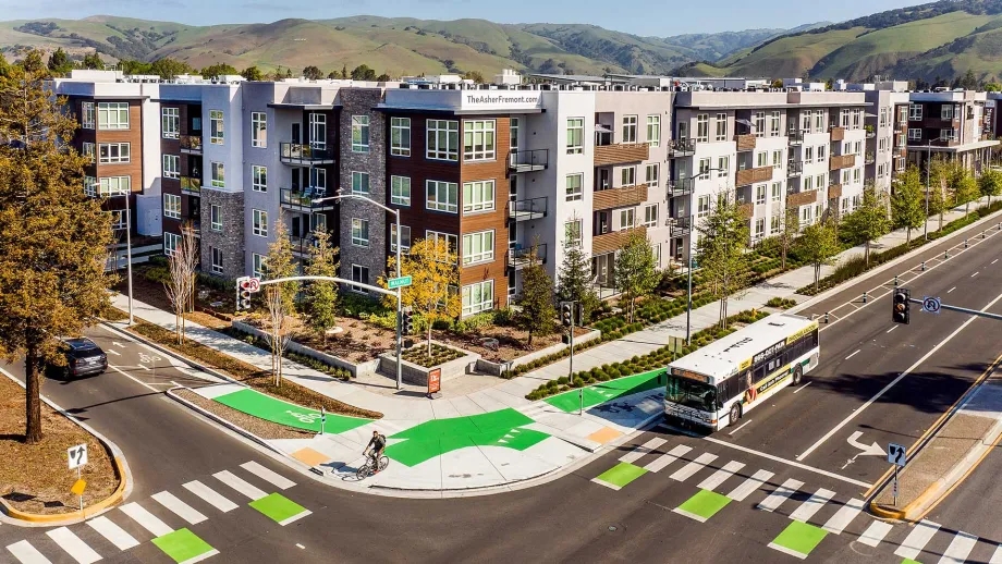 An intersection with transit and bike lanes in front of a large apartment building.