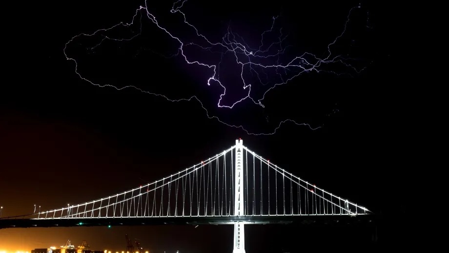 The San Francisco-Oakland Bay Bridge at night during a lightning storm.