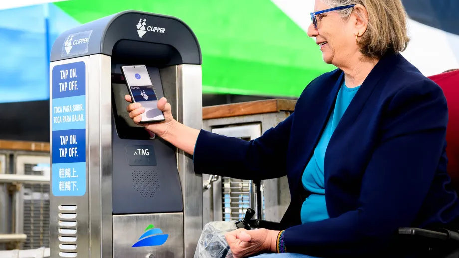 A person in a wheelchair using Clipper on her phone to pay for a ferry ride.