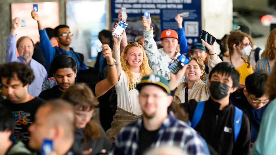 A crowd of transit riders show off their Clipper cards.
