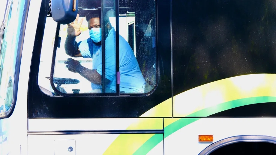 Bus driver wearing face mask waving hello
