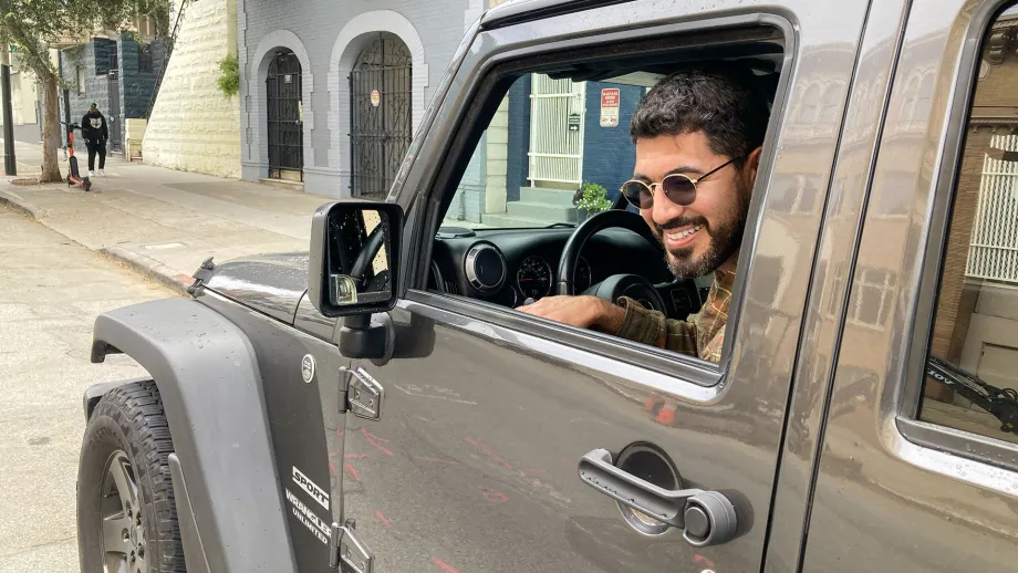 A driver demonstrating the Dutch Reach by using his right hand to open the car door.