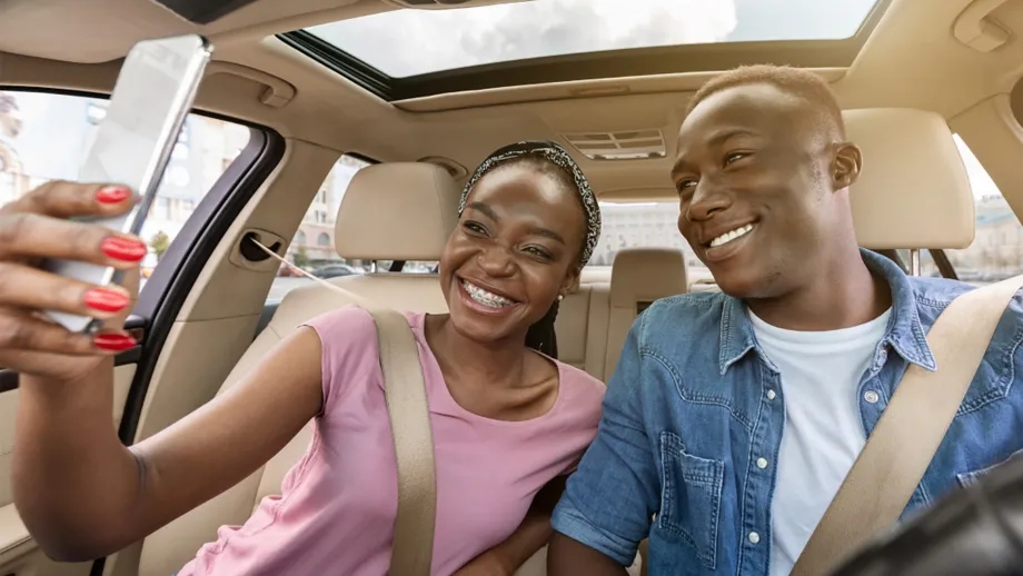 Two people in the front seat of a car taking a selfie for the RideFlag app.