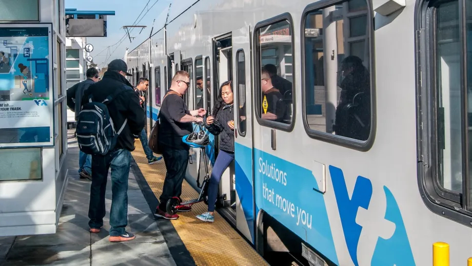 People enter and exit a VTA light rail train.